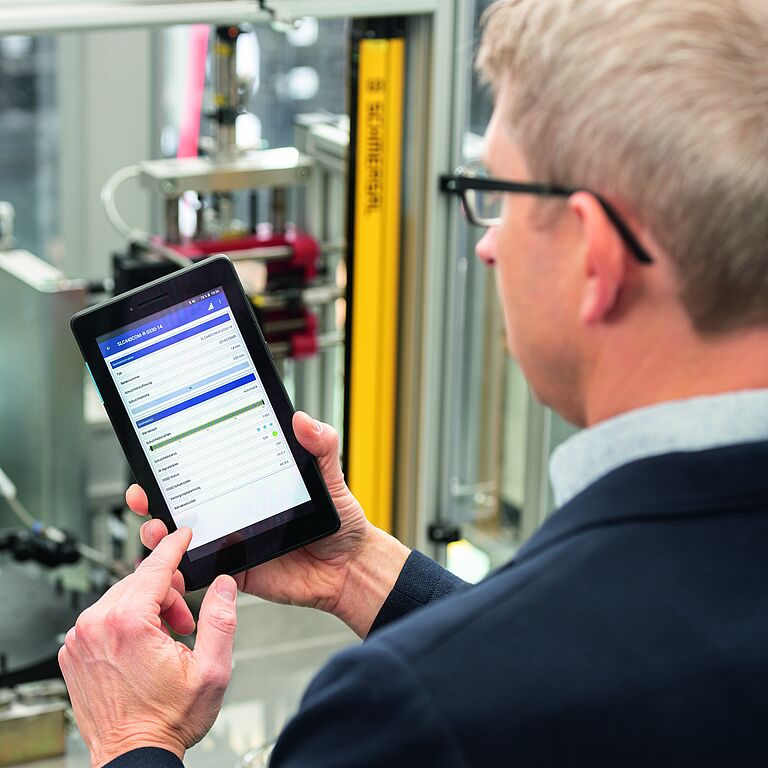 photo, man holding smartphone with SLC ASSIST APP displayed