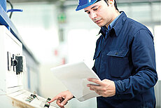 worker consult manual while operating machine